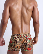 Male model's back view showing the CATS N'ROSES beach shorts for men featuring animal print of brown cheetah with red roses by Bang! Miami.