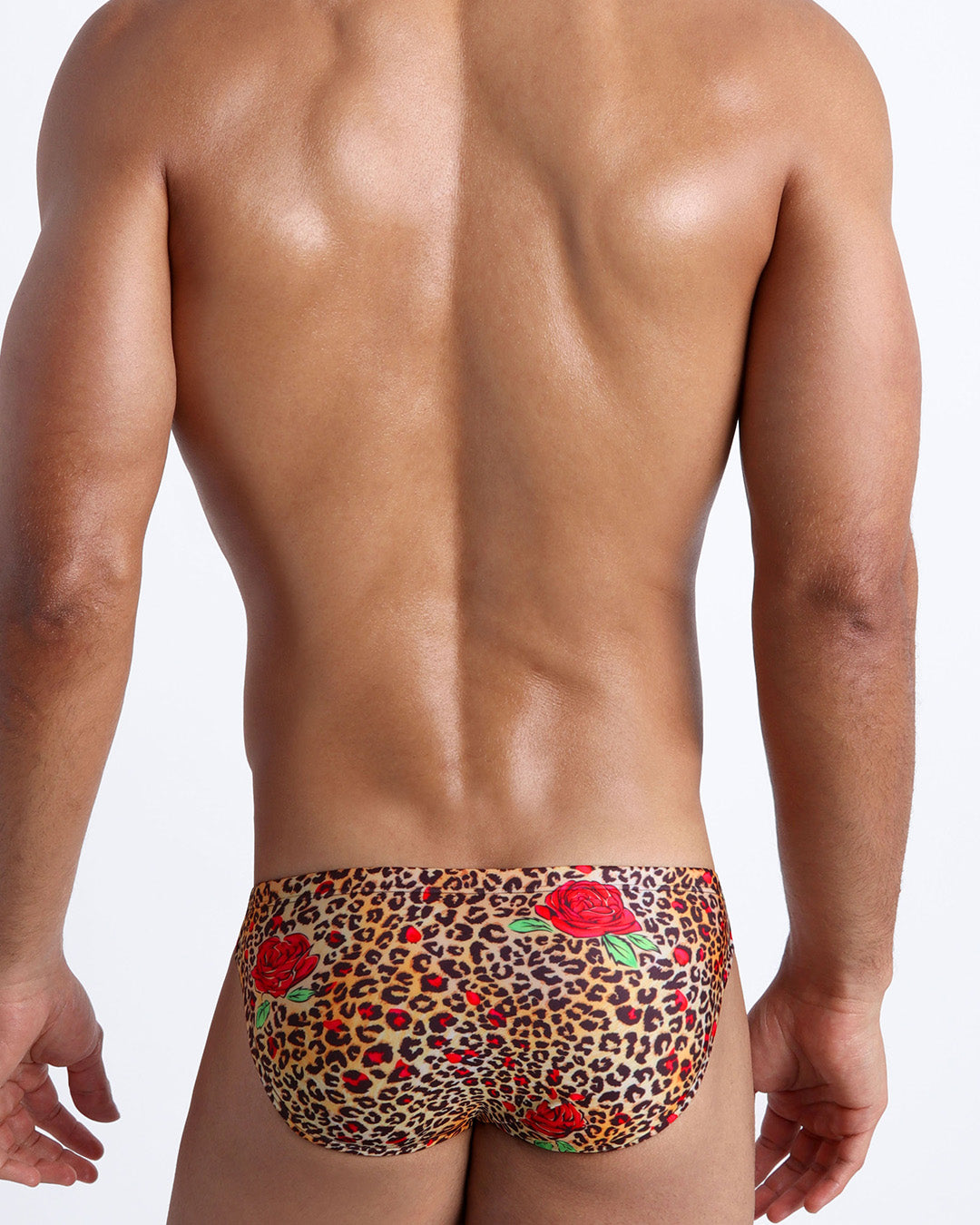 Male model's back view showing the CATS N'ROSES beach mini-briefs for men featuring animal print of brown cheetah with red roses by Bang! Miami.