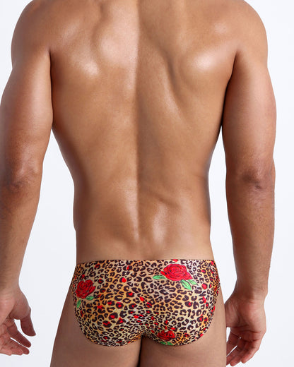 Male model's back view showing the CATS N'ROSES beach mini-briefs for men featuring animal print of brown cheetah with red roses by Bang! Miami.