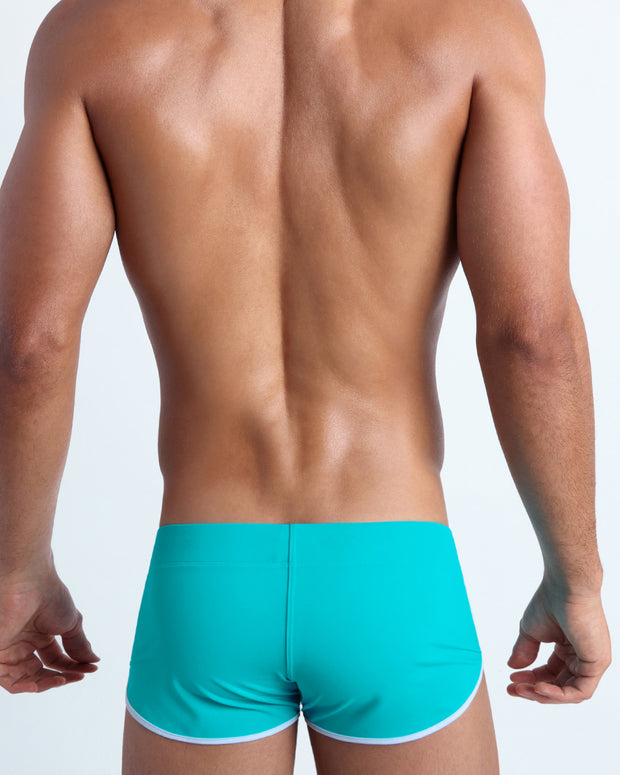 Back view of a male model wearing men’s swim shorts in azure color by the Bang! Clothes brand of men&