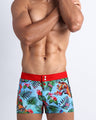 Front view of a sexy man wearing the DISCO JUNGLE beach shorts featuring a fun and enegetic jungle graphics in bold colors, with a tiger illustration.