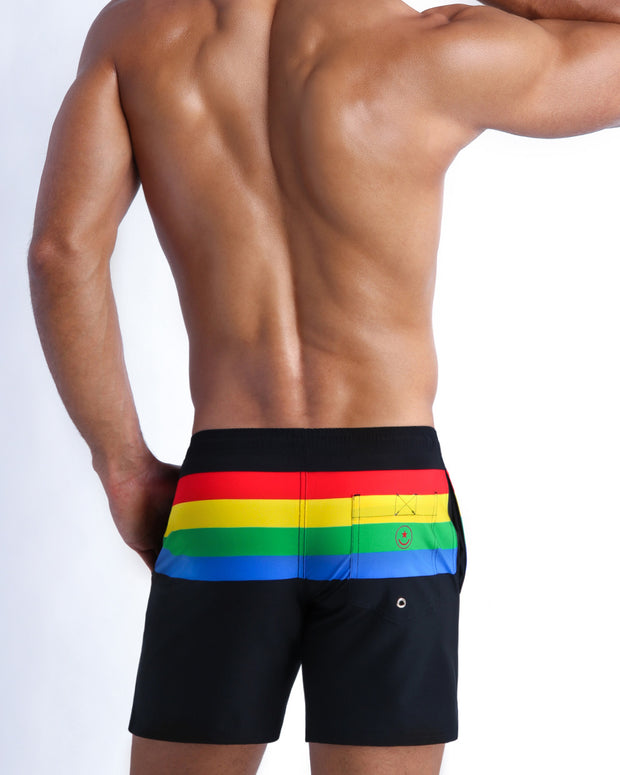 Back side of the FOREVER STRIPES VOL 1 beach mens swimsuit in black with colored bands in green, red, yellow and blue.