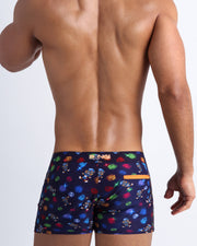 Back view of model wearing the HEY MISTER TJ (CLUB MIX) Men’s beach shorts by BANG! with clubbing and disc-jockey details in dark colors made by the Bang! official brand of men's beachwear.