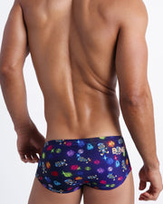 Back view of model wearing the HEY MISTER TJ (CLUB MIX) Men’s swim sunga by BANG! with clubbing and disc-jockey details in dark colors made by the Bang! official brand of men's beachwear.