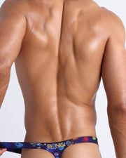 Back view of model wearing the HEY MISTER TJ (CLUB MIX) Men’s swim bikini by BANG! with clubbing and disc-jockey details in dark colors made by the Bang! official brand of men's beachwear.