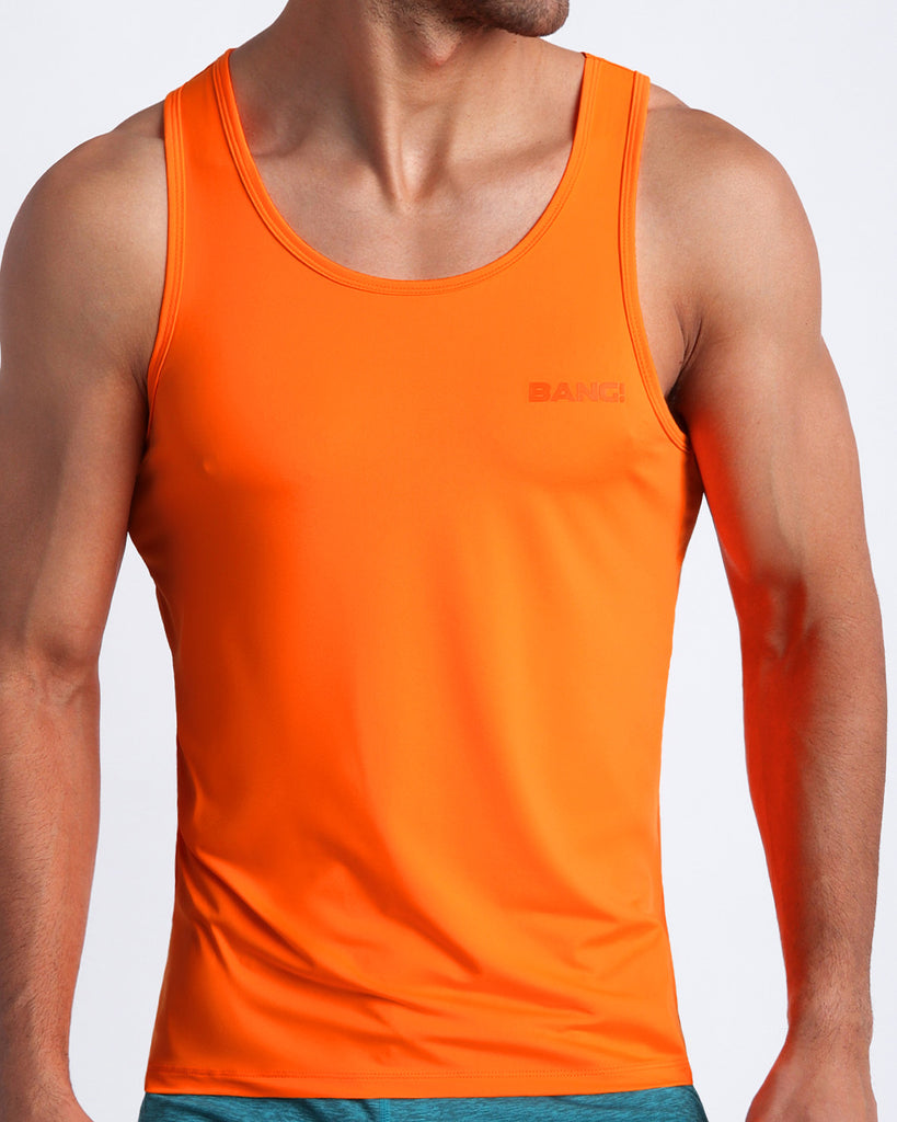 Frontal view of male model wearing the IMPACT ORANGE in a hot orange men's gym tank top by the Bang! brand of men's beachwear from Miami.