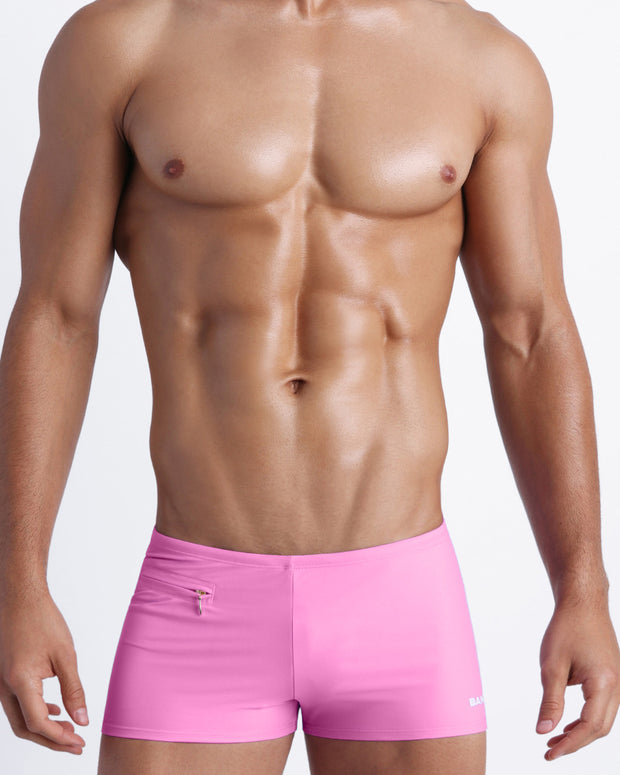 Frontal view of a sexy male model wearing men’s swimsuit with mini pockets in light pink color by the Bang! Menswear brand from Miami.