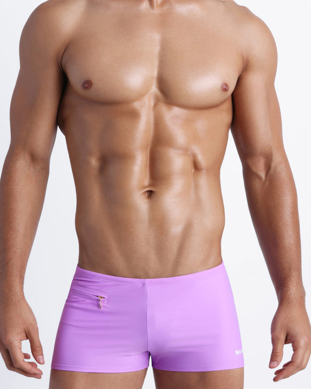 Frontal view of a sexy male model wearing a men swimsuit with mini pockets in mauve color made with Italian-made Vita By Carvico Econyl Nylon by the Bang! Menswear brand from Miami.