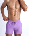 Frontal view of sexy model wearing the NEO VIOLET men’s all-purpose swimwear bottoms in a neon purple color by the Bang! brand of men's beachwear from Miami.