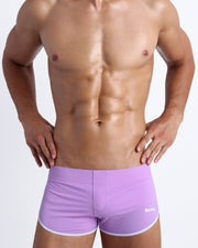 Frontal view of a sexy male model wearing men’s swimsuit in lilac color by the Bang! Menswear brand from Miami.