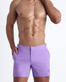 Frontal view of model wearing the NEO VIOLET. Men’s tailored shorts featuring a lilac color t by the Bang! brand of men's beachwear from Miami.