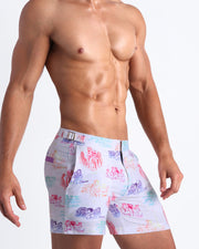 Side view of model wearing the OH L'AMOUR men’s shorts for the beach by Bang! Miami, with white background and love scenes in pastel colors.