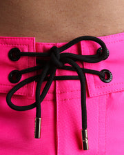 Close-up view of men’s summer beach shorts by BANG! clothing brand, showing black cord with custom branded golden cord ends, and matching custom eyelet trims in gold.