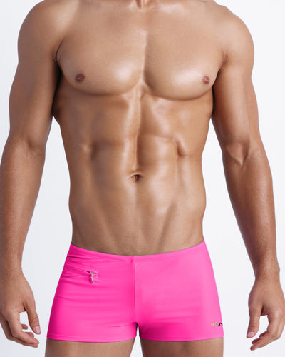 Frontal view of a sexy male model wearing men’s swimsuit with mini pockets in bright pink color by the Bang! Menswear brand from Miami.