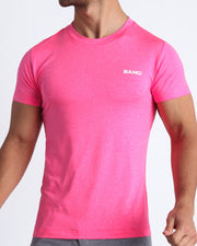 Frontal view of male model wearing the PINKTENSITY in a solid fluorescent pink quick-dry workout shirt by the Bang! brand of men's beachwear from Miami.