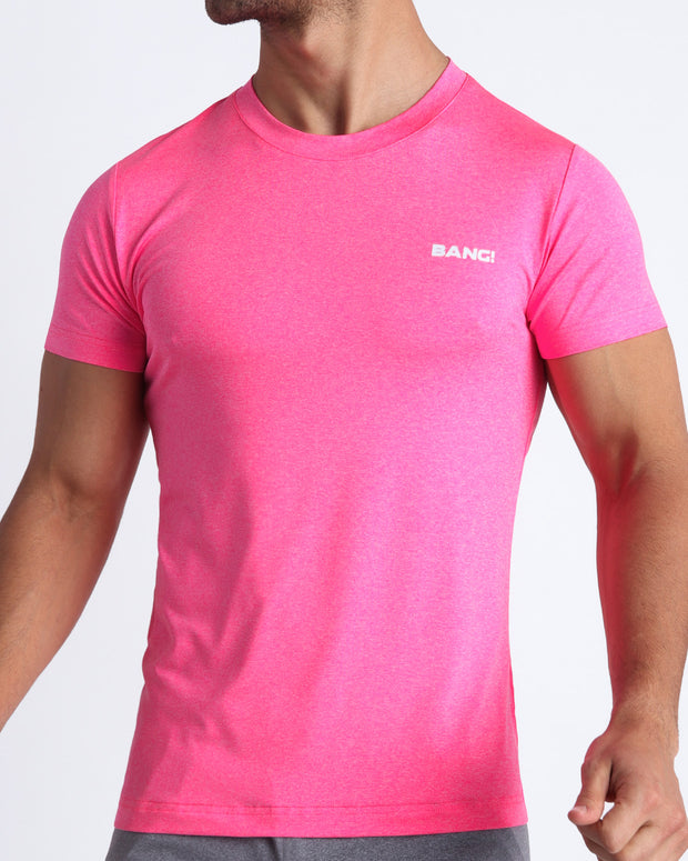 Frontal view of male model wearing the PINKTENSITY in a solid fluorescent pink quick-dry workout shirt by the Bang! brand of men&