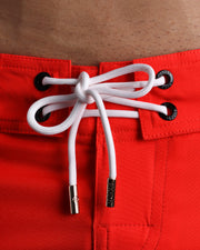 Close-up view of men’s summer Baywathc beach shorts by BANG! clothing brand, showing white cord with custom branded golden cord ends, and matching custom eyelet trims in gold.