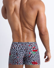 Male model's back view showing the SO RED THE ROSE beach shorts for men featuring animal print of black and white cheetah with red roses by Bang! men's swimwear.