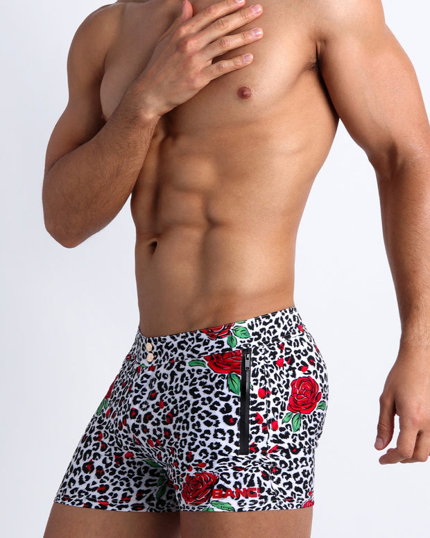 Lateral view of a man wearing the SO RED THE ROSE Summer men swimwear by Bang! Clothes black & white leopard animal print with red roses.