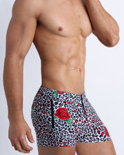 Lateral view of a man wearing the SO RED THE ROSE Summer men swimwear by Bang! Clothes black & white leopard animal print with red roses.