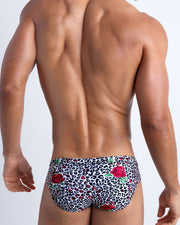 Male model's back view showing the SO RED THE ROSE beach briefs for men featuring animal print of black and white cheetah with red roses by Bang! men's swimwear.