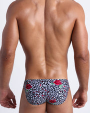 Male model's back view showing the SO RED THE ROSE beach mini-briefs for men featuring animal print of black and white cheetah with red roses by Bang! men's swimwear.