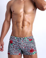 Frontal view of model wearing the SO RED THE ROSE men’s square leg swim trunks featuring leopard print in white and black tones with red roses by the Bang! menswear brand.