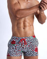 Frontal view of model wearing the SO RED THE ROSE men’s beach shorts featuring leopard print in white and black tones with red roses by the Bang! menswear brand.