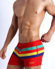 Side view of the Stripe'A'Pose ROUX swim trunks for men in hot red colors with stripes in teal, bright red, yellow and violet by Bang! Clothing of Miami.