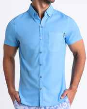 Male model wearing the MAGNET BLUE men’s short-sleeve stretch shirt in sky blue color by the Bang! brand of men's beachwear from Miami.