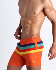 Side view of the Stripe'A'Pose REMIX swim trunks with side pockets for men in hot orange with color stripes in  purple, aqua, red and yellow by Bang! Clothing of Miami.