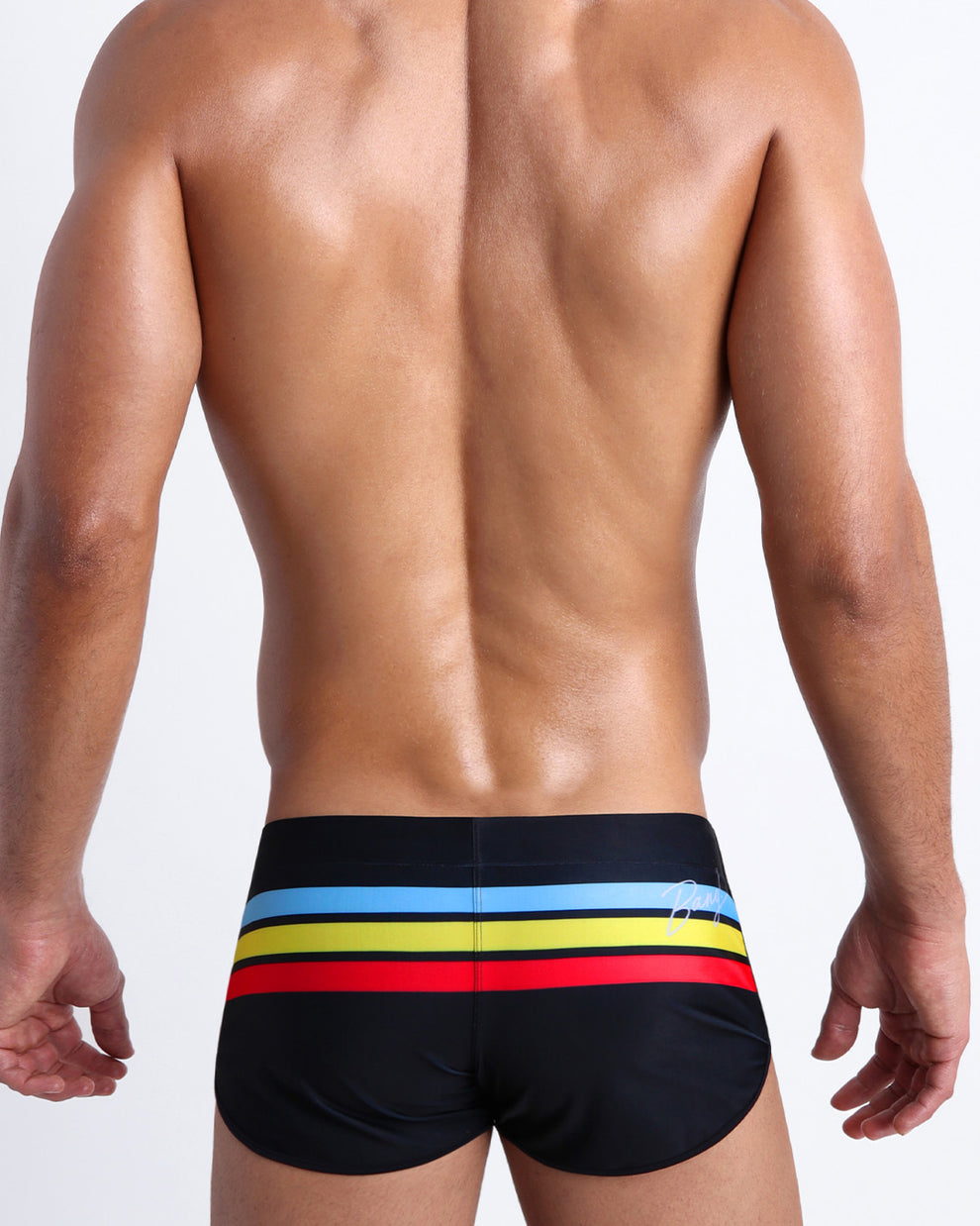 Back side view of male model wearing men's swimwear in black color with color stripes in turquoise blue, yellow, and bold red.
