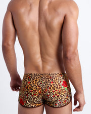 Male model's back view showing the CATS N'ROSES beach beach shorts for men featuring animal print of brown cheetah with red roses by Bang! Miami.