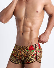Lateral view of a man wearing the CATS N'ROSES Summer men swimsuit by Bang! Clothes in brown leopard animal print with red roses.