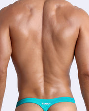 Back view of a male model wearing men’s swim thongs in azure color by the Bang! Clothes brand of men's beachwear.