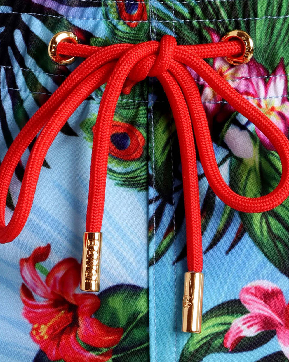 Close-up view of the DISCO JUNGLE men’s summer shorts, showing custom branded golden cord-ends, and matching custom eyelet trims in gold by Bang! Miami.