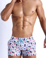 Frontal view of model wearing the HEY MISTER TJ (POOLSIDE MIX) Men’s beach shorts in white with colorful headphones and disc shapes and a dj tiger print by Bang! men's beachwear.