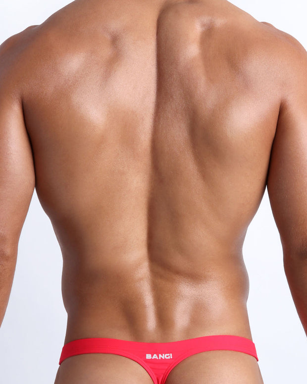Back view of a male model wearing men’s swim thong in neon red by the Bang! Clothes brand of men&