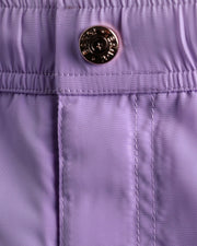 Close-up view of the  NEO VIOLET men’s summer mini shorts, showing custom branded metal button in gold.