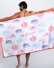 Frontal view of sexy male model showing the OH L'AMOUR unisex lightweight towel in white with colorful scenes of iconic couples kissing and in love.