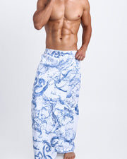 Model showing the SPLASH quick-dry microfiber towel with matching swim briefs for the beach in white and blue color with graphics of water and wet letters.