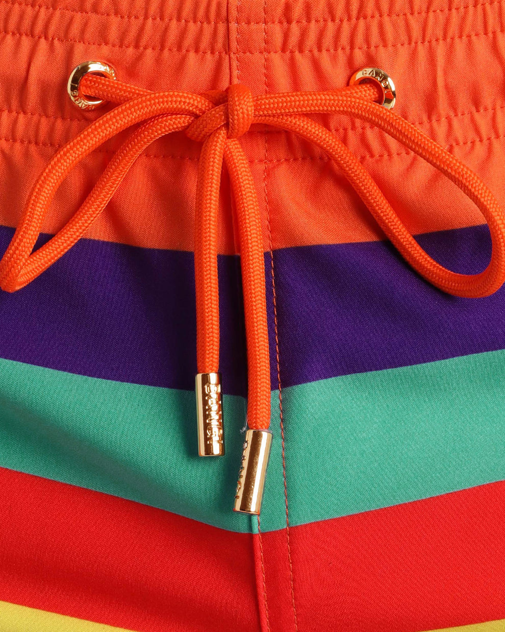 Close-up view of inseam and details of Stripe'A'Pose REMIX swimsuit for men, with orange cord and custom branded golden cord-ends, and matching custom eyelet trims in gold.