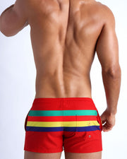 Back side of the Stripe'A'Pose ROUX men’s beach trunks in red with colored bands in green, red, yellow and blue by Bang! Miami.