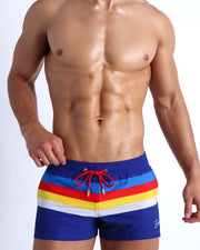 Male model wearing the Stripe'A'Pose men's beach shorts by the Bang! Clothes brand of men's swimwear from Miami.