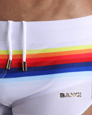 Close-up view of trims of STRIPES ON 45 waistband drawstring, with white cord and custom branded golden cord-ends, and matching custom eyelet trims in gold.