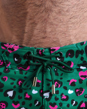 Close-up view of men’s summer beach shorts by BANG! clothing brand, showing green cord with custom branded golden cord ends, and matching custom eyelet trims in gold.
