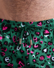 Close-up view of the CAMO CHAMELEON men’s summer shorts, showing green cord with custom branded golden cord ends, and matching custom eyelet trims in gold.