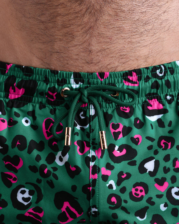 Close-up view of the CAMO CHAMELEON men’s summer shorts, showing green cord with custom branded golden cord ends, and matching custom eyelet trims in gold.