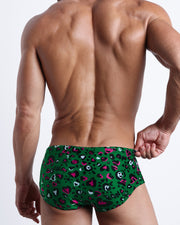 Back view of a Male model wearing Brazilian Beach Sunga Swimsuit for men featuring a black, white, hot pink leopard animal and hearts print by the Bang! Clothes brand of men's beachwear.