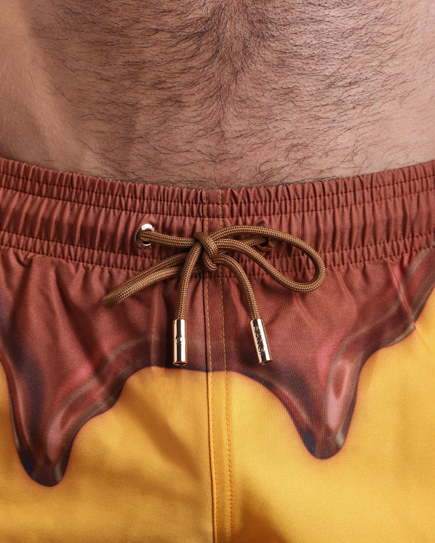 Close-up view of the CHOCO-BANG men’s summer shorts, showing brown cord with custom branded golden cord ends, and matching custom eyelet trims in gold.